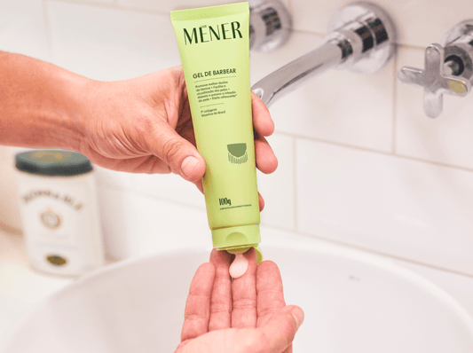 Mão aplicando gel de barbear MÉNER na palma, mostrando textura do produto para facilitar o deslize da lâmina.
